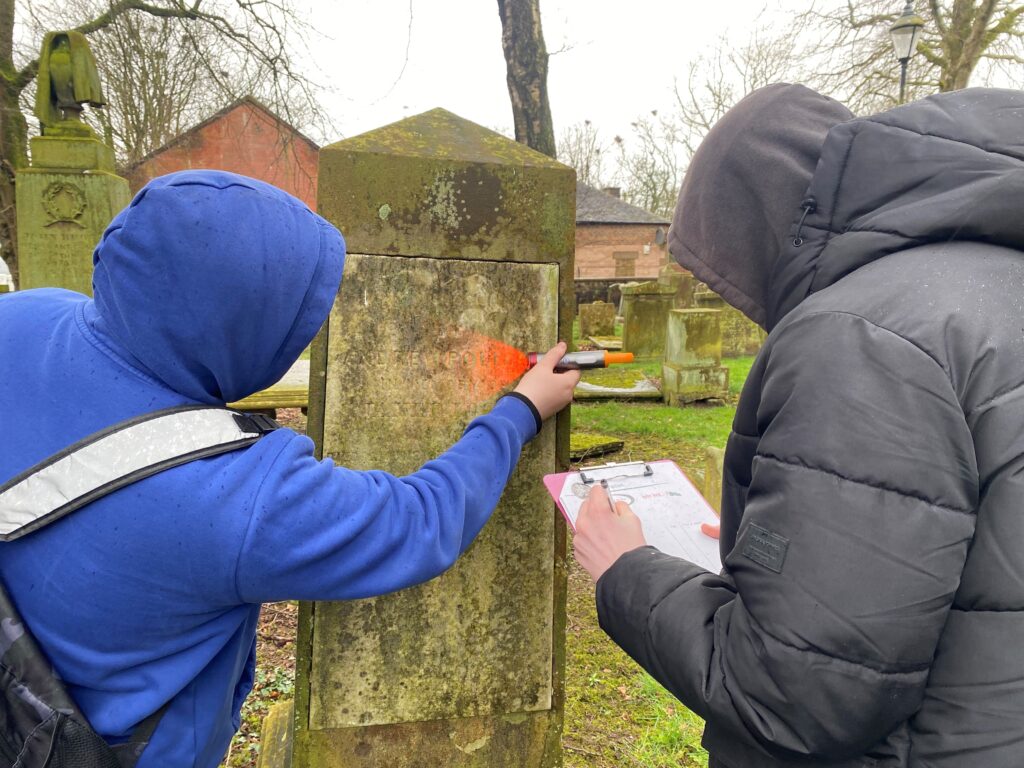 Two people recording a gravestone